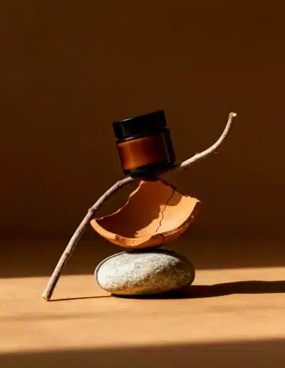 Création d’images par IA : flacons ambrés sur fond brun, composition naturelle avec pierres et bois, lumière chaude et direction artistique minimaliste