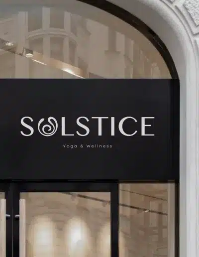 Logo minimaliste blanc pour la marque Solstice Yoga & Wellness sur façade noire, identité visuelle apaisante et contemporaine créée par Clemara Studio